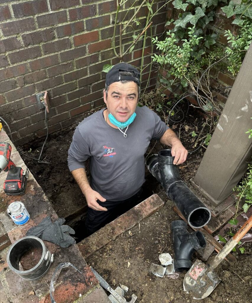 Plumber repairing sewer backup in Seattle home during outage.