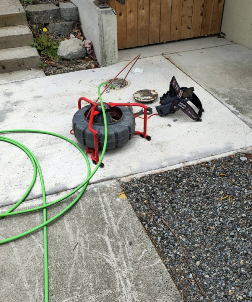 Technician holding flexible sewer camera cable and monitor displaying live pipe footage.